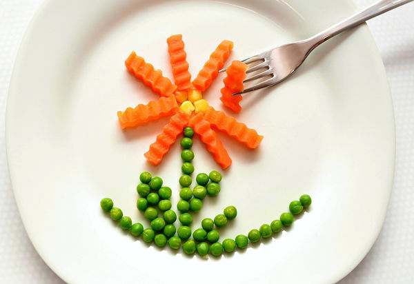 Jak naučit dítě zdravě jíst? Fotografie zeleniny na talíři ve tvaru květiny.