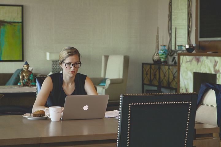 Fotografie ženy sedící u stolu a pracující na PC