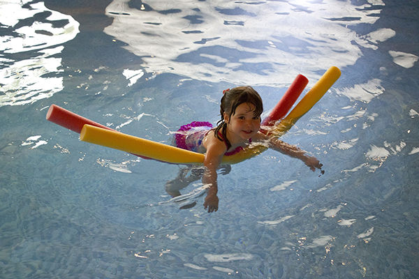 Fotografie dítěte jak plave s plovacími deskami v bazénu. jak učit dítě plavat
